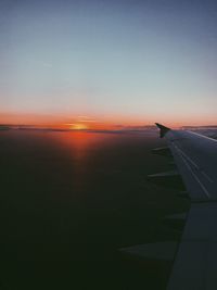 Airplane wing against sky during sunset