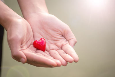 Cropped hands of woman holding red heart shape