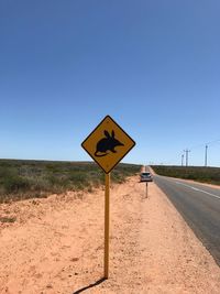 Road sign against clear blue sky