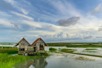 Houses by lake against sky