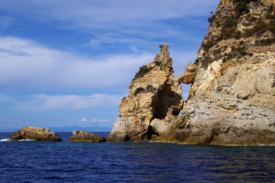 Rock formation by sea against sky