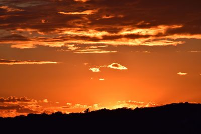 Scenic view of silhouette landscape against dramatic sky during sunset