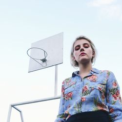 Low angle view of young woman against clear sky