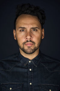 Portrait of young man against black background