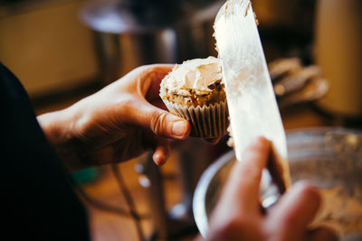 Close-up of person icing cupcake