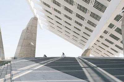 Unrecognizable person riding bicycle under solar panel