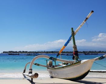 Fishing boat on beach against sky