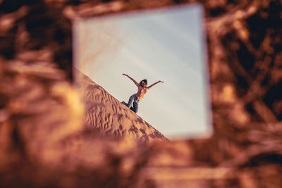 Reflection of woman kneeling on ground in mirror