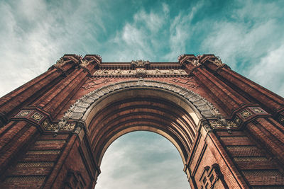 Low angle view of triumphal arch against cloudy sky