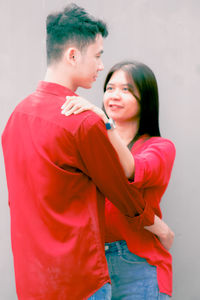 Side view of boy standing against wall