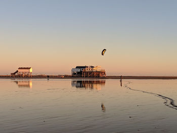 Woman kiteboarding at beach against clear sky