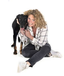 Portrait of woman with dog sitting against white background