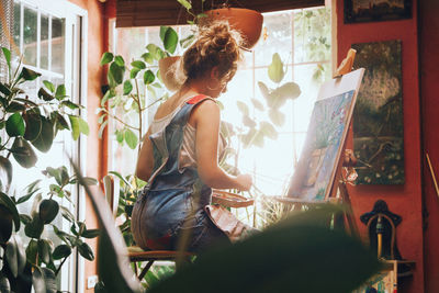 Young woman painting on easel