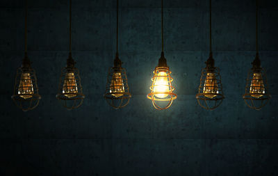 Close-up of illuminated light bulb hanging in darkroom