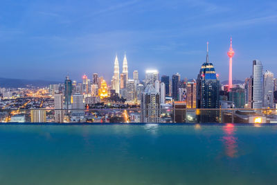 Illuminated buildings in city against sky