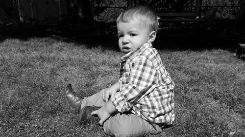 Baby boy sitting on grassy field