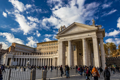 Group of people in front of historical building against cloudy sky