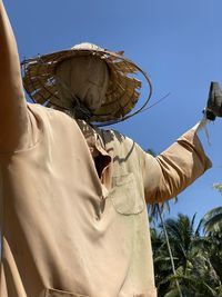 Low angle view of man holding umbrella against clear blue sky