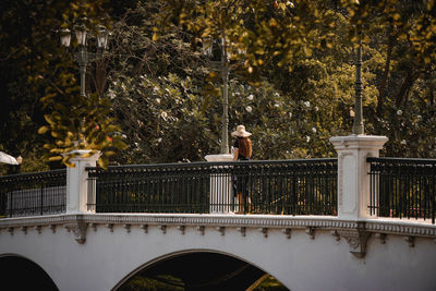 Reflection of man on railing against trees