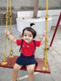 Portrait of smiling girl sitting on swing