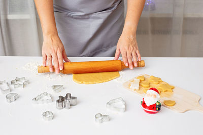 Women's hands are rolling out the dough for christmas cookies, on a white table