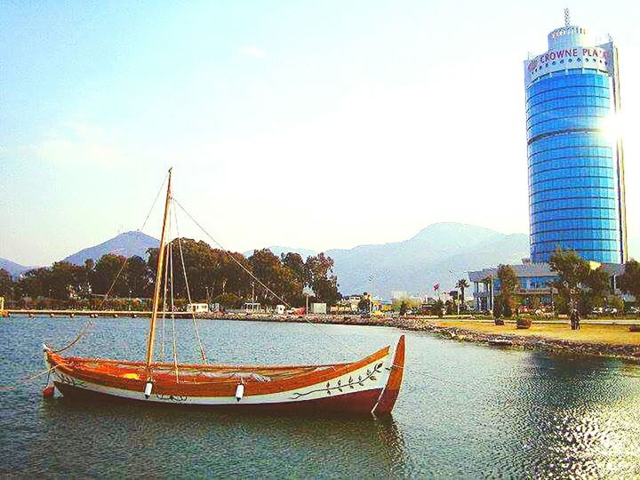 water, architecture, built structure, building exterior, clear sky, city, waterfront, transportation, river, nautical vessel, sky, mountain, copy space, blue, sea, outdoors, tower, travel destinations, day, boat