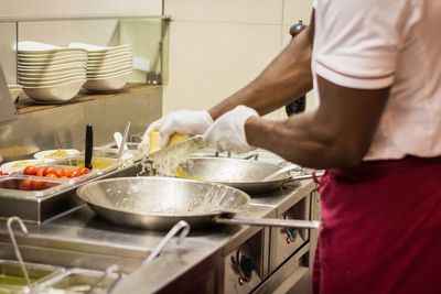 Midsection of chef preparing food in kitchen at restaurant