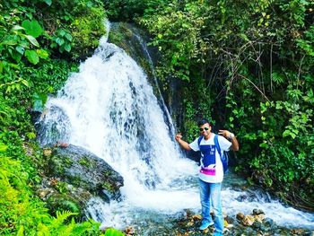 Man standing on rock against waterfall