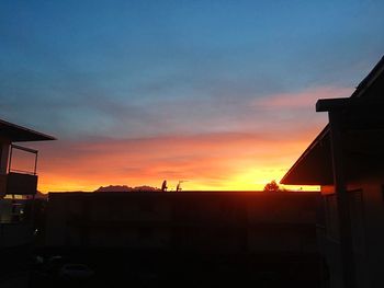 Silhouette houses and buildings against sky during sunset