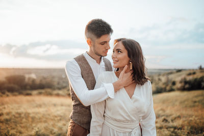 Young couple standing on land against sky