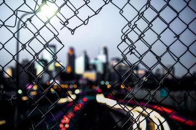 Defocused image of city seen through chainlink fence