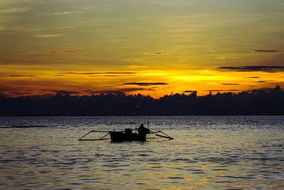 Silhouette of man in rowboat during sunset