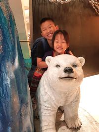 Portrait of siblings sitting on bear statue