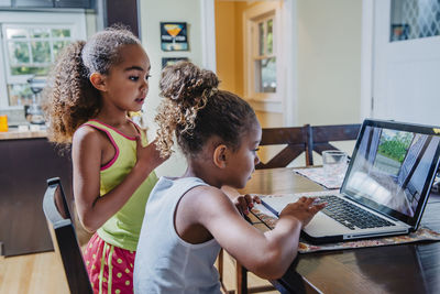 Sisters using laptop at home