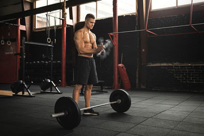 Full length of shirtless man working out at gym