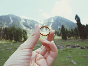 Close-up of person holding ring against mountain