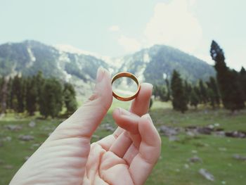 Midsection of person holding sunglasses against mountain