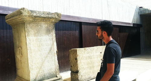 Side view of young man standing against wall