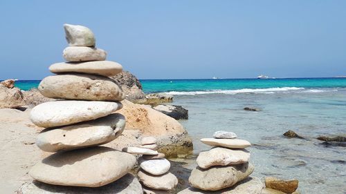 Stack of pebble stones at beach against sky