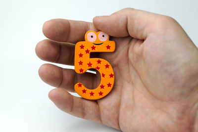 Close-up of hand holding toy against white background