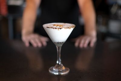 Close-up of hand holding drink served on table