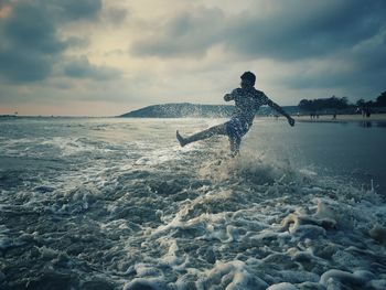 Man surfing in sea against sky