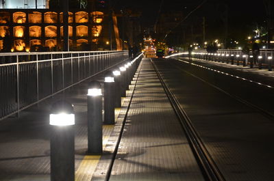 Illuminated railroad tracks in city at night