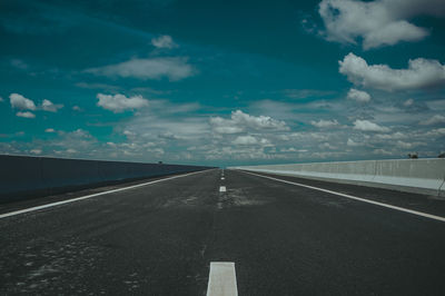 Surface level of empty road against cloudy sky