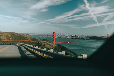 Bridge over road by sea against sky