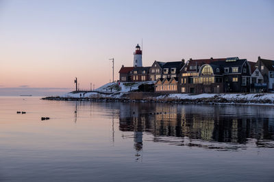 Reflection of buildings in sea against clear sky