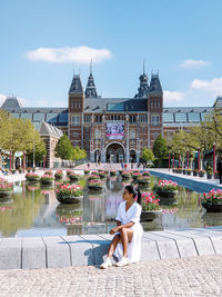 Woman sitting by pond in city