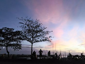 Silhouette people by tree against sky during sunset