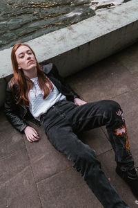 High angle portrait of young woman lying on street