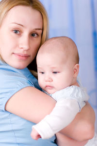 Portrait of baby and mother on blue background